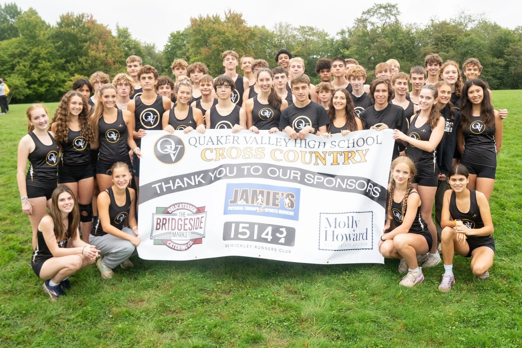 Quaker Valley High School Cross Country team with sponsor banner