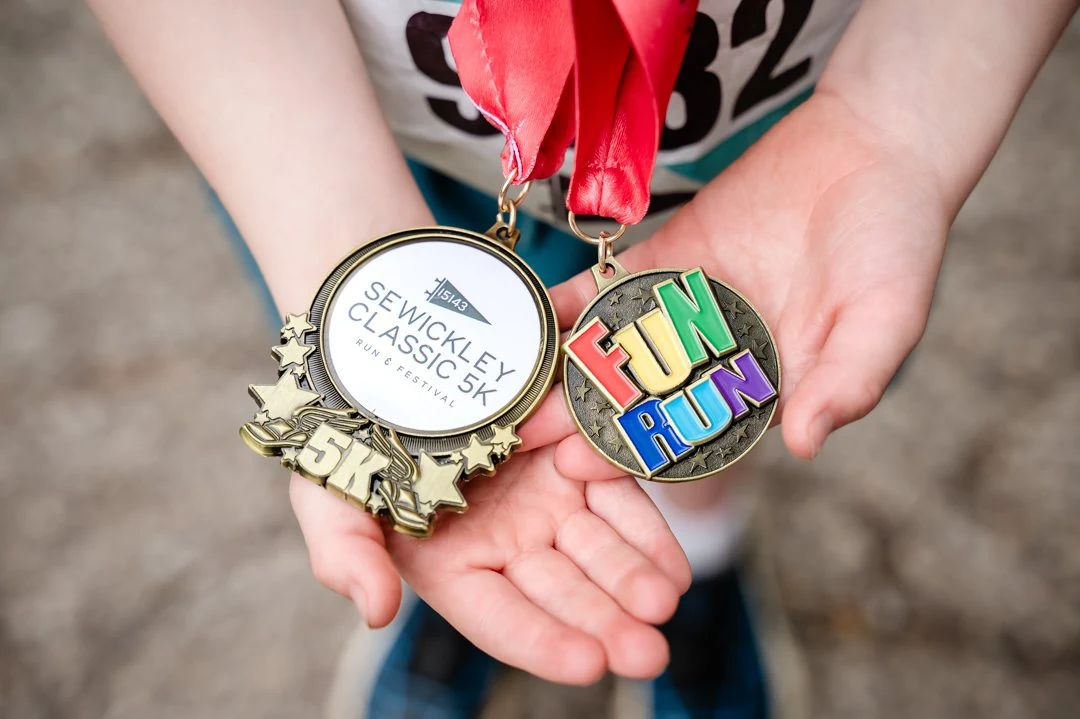 Sewickley Classic and Fun Run medals held in a child's hands